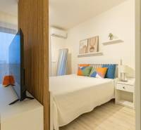 1-Zimmer-Wohnung mit Bett, Fernseher und dekorativen Kissen. Boden mit Holzdekor.