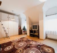 Ein Zimmer in einem Einfamilienhaus mit einem Holzboden, einem Fernseher und einem Schrank.