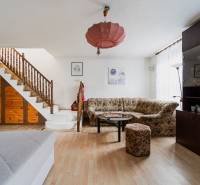 Wohnzimmer in einem Einfamilienhaus mit Holztreppe, Sofa, Schrank und Boden mit Holzdekor.