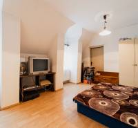 Ein Schlafzimmer in einem Einfamilienhaus mit einem Boden in Holzoptik, einem älteren Fernseher und Stauraum.