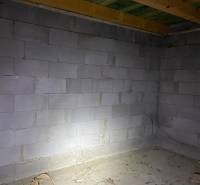 Ein roher Raum in einer Hütte mit Betonwänden und einer Holzdecke.