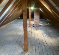 Dachboden in einer Hütte mit Holzbalken und einem gemauerten Kamin, Boden mit Holzdekor.