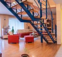 Innenraum der Villa mit Holzboden, Treppe und rotem Sofa.