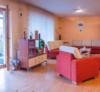 Wohnzimmer in einer Villa mit rotem Sofa und Boden in Holzoptik.