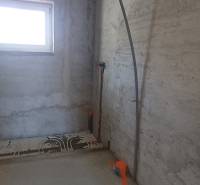 Innenraum eines im Bau befindlichen Einfamilienhauses mit Fenster und Vorbereitung für die Installation von Leitungen.