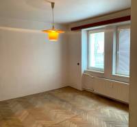 Ein Zimmer in einer 2-Zimmer-Wohnung mit einem Boden in Holzdekor und einem Fenster mit Jalousien.