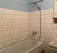 Badezimmer in einer 2-Zimmer-Wohnung mit Badewanne, weißen Fliesen und Duschkopf.