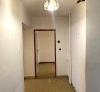 Ein Flur mit Fliesen und einem Kronleuchter, der zu einem Raum in einer Zweizimmerwohnung führt.