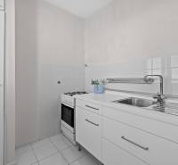 Küche in einer Einzimmerwohnung mit weißer Küchenzeile und Herd.