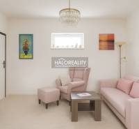 Wohnzimmer mit pastellfarbenem Sofa und Sessel in einem Einfamilienhaus, dekorative Bilder an den Wänden.