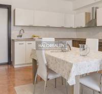 Eine Küche in einem Einfamilienhaus mit einer weißen Küchenzeile und einem Esstisch mit vier Stühlen.