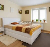 Schlafzimmer in einem Einfamilienhaus mit Bett, Nachttisch und Fenster mit Zimmerpflanzen.