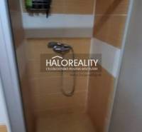 Duschkabine in einer Einzimmerwohnung mit orangefarbenen Fliesen und Stauraum an der Wand.