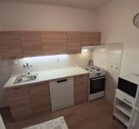 Küche in einer 3-Zimmer-Wohnung mit Küchenzeile, Herd, Geschirrspüler und Bodenbelag in Holzoptik.