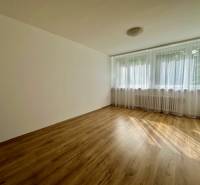 Ein heller Raum mit Holzboden und einem großen Fenster in einer 3-Zimmer-Wohnung.