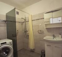 Badezimmer mit Duschkabine, Waschmaschine und Spiegelschrank in einer 3-Zimmer-Wohnung.