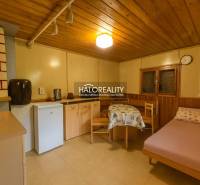 Ein Zimmer mit einem Holzboden, einfacher Einrichtung, einem Bett und einer Kochnische.