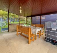Überdachte Terrasse mit Tisch, Bänken und Blick auf die Gärten in Bytča.