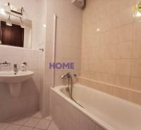 Badezimmer in einer 2-Zimmer-Wohnung mit Badewanne, Waschbecken und Spiegel.