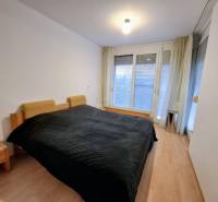 Schlafzimmer in einer 2-Zimmer-Wohnung mit Holzboden und großen Fenstern.