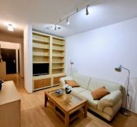 Wohnzimmer in einer Zweizimmerwohnung mit cremefarbenem Sofa und Holzboden.