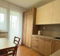 Küche in einer 3-Zimmer-Wohnung mit Holzdekor und hellem Möbeln, elegante Blumen auf dem Tisch.