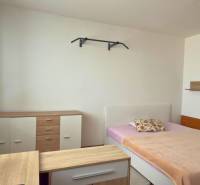 Schlafzimmer mit Bett, Schrank und dekorativen Blumen in einer 3-Zimmer-Wohnung.