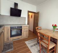 Küche in einer 3-Zimmer-Wohnung mit Holzelementen, Esstisch und Küchenzeile.