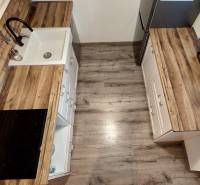 Küche in einer 3-Zimmer-Wohnung mit Holzboden und Küchenschränken.