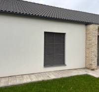 Das Äußere des Einfamilienhauses in der Fialkova-Straße in Tomášov mit Ziegelverkleidung und Rasen.