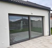 Ein Einfamilienhaus in Tomášov in der Fialkova-Straße mit Schiebetüren und einer Terrasse.