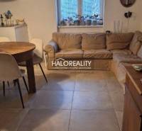 Wohnzimmer einer 3-Zimmer-Wohnung mit Sofa, Esstisch und Fliesenboden.