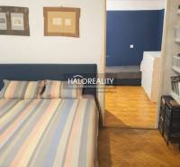 Schlafzimmer in einer 3-Zimmer-Wohnung mit Holzboden und bunter Bettwäsche.