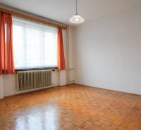 Ein Zimmer mit einem Holzboden, weißen Wänden und orangen Vorhängen in einem Einfamilienhaus.