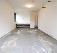 Garage in einem Einfamilienhaus mit Betonboden und weißen Wänden.