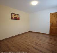 Ein Zimmer mit einem Holzboden, einem Bild an der Wand und Holztüren.