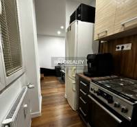 Küche in einer Einzimmerwohnung mit Holzboden, Herd und Kühlschrank.