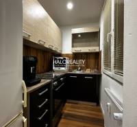 Küche in einer Einzimmerwohnung mit Holzboden und dunklen Schränken.