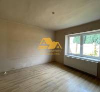 Ein Zimmer mit einem Holzboden und einem großen Fenster in einem Einfamilienhaus.