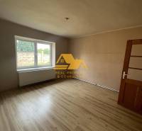 Ein Zimmer mit einem großen Fenster und einem Boden in Holzoptik in einem Einfamilienhaus.