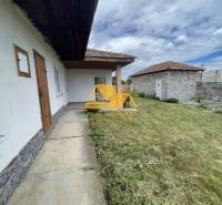 Ein Einfamilienhaus in der Svodin-Straße in Svodín mit einem grasbewachsenen Hof und einer Steinmauer.
