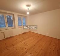 Ein Zimmer eines Einfamilienhauses mit einem Holzboden, großen Fenstern und Heizkörpern.