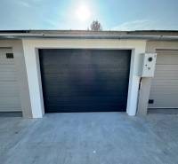 Garagen in der Slnečná-Straße in Komárno mit dunklen Toren und Betonfläche.