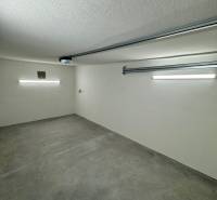 Innenraum einer Garage mit Betonboden und Beleuchtung im Garagenbereich.