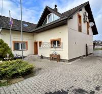 Ein Einfamilienhaus in Prievidza mit einem asphaltierten Hof, Garten und Satellitenschüssel.