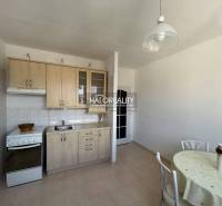 Küche in einer Einzimmerwohnung mit Küchenzeile, Esstisch und hellem Interieur.