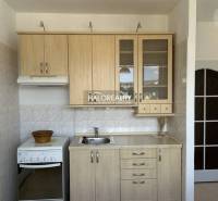 Küche in einer Einzimmerwohnung mit Holzelementen und weißen Fliesen.