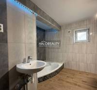 Badezimmer eines Einfamilienhauses mit Badewanne, Waschbecken und Boden mit Holzdekor.