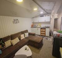 Wohnzimmer in einer Hütte mit bequemer Couch, Küchenzeile und dekorativem Wandbelag.