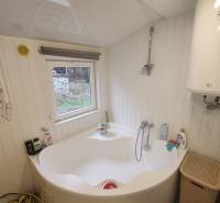 Das Badezimmer in der Hütte zeigt eine Badewanne, einen Boiler und ein kleines Fenster mit Aussicht.